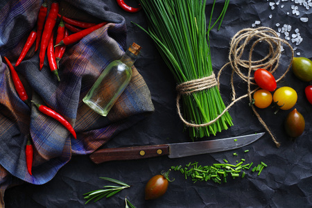 Rustic vegetable composition with chives onions, tomatoes and pepper, drapery and knife. Top view.