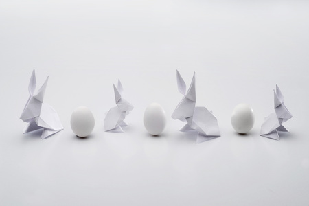 White Easter bunnies made in the technique of origami and eggs on a white background.の写真素材