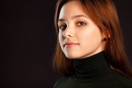 Closeup headshot portrait of redhead woman on dark backgroundの写真素材