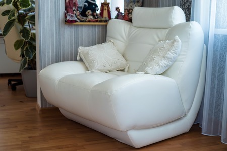 White leather armchair with cushions in roomの写真素材