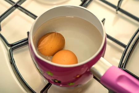 Boiling two eggs in water in stainless steel panの写真素材
