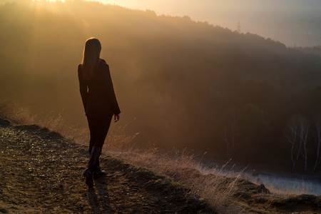 Female hiker standing on edge of rock at sunriseの写真素材