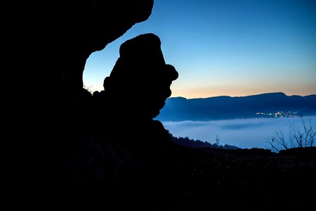 Slhouette of a rock resembling head with hatの写真素材