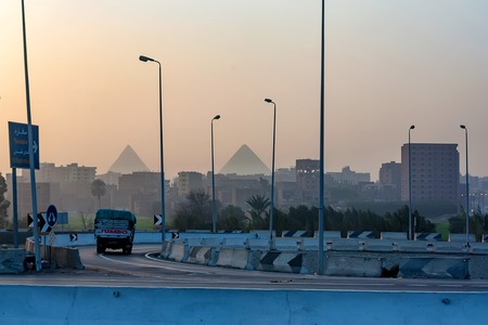 GIZA, EGYPT- FEBRUARY 2010: City street with Pyramids in backgroundのeditorial素材