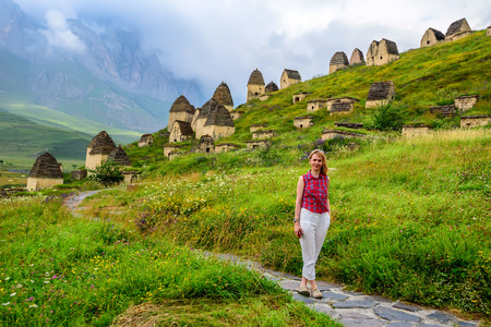 Female hiker stands against old tombs of Dargavs