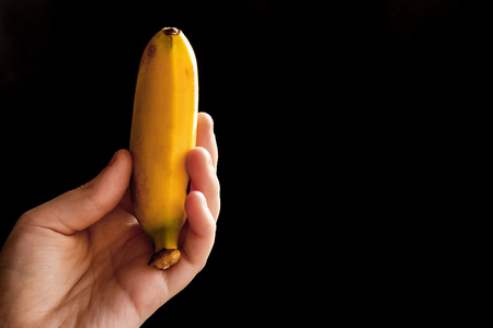 Hand holds banana of black backgroundの写真素材