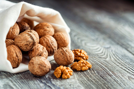 Walnuts in sack on wooden backgoundの写真素材