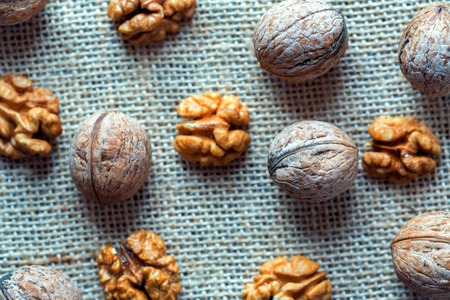 Walnuts and kernels on burlap on wooden backgound