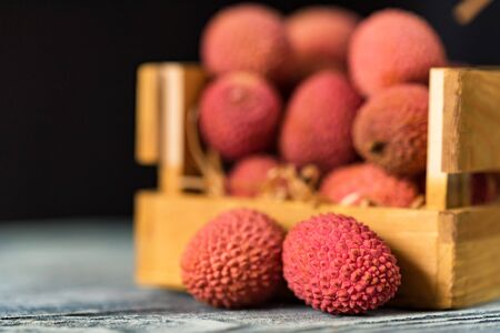 Close up lychee fruit in wooden box on black backgroundの写真素材