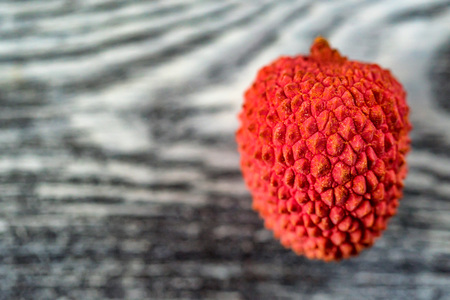 Single lychee on wooden background close