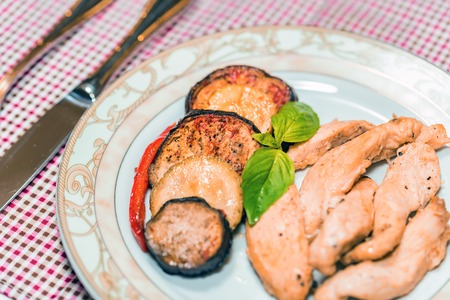 Pieces of roasted chicken and vegetables on plateの写真素材