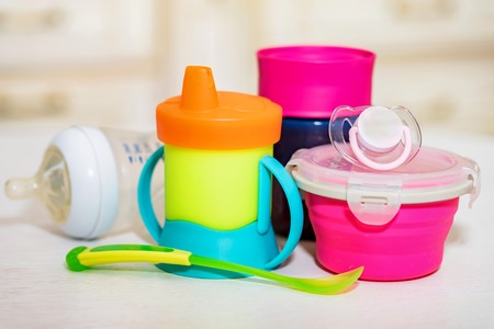 Bright plastic baby dishes on table