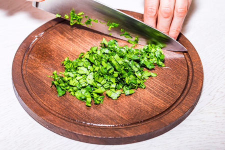 Female hands chopping herbs on wooden boardの写真素材