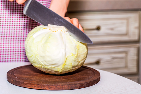 Female hands cut cabbage on wooden boardの写真素材