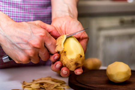 Hands peeling potatoes closeの写真素材