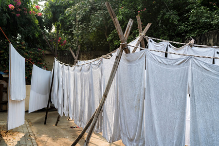 White sheets hang on ropes in Indian streetの写真素材