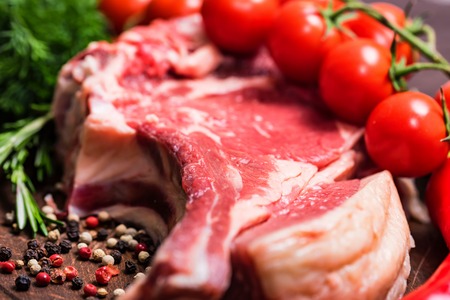 Raw beef steak with pepper, herbs and tomatoesの写真素材