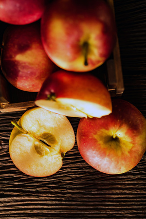Apples whole and cut in halves on wooden surfaceの写真素材