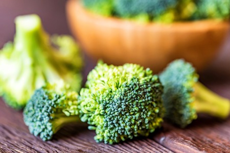 Fresh broccoli in wooden bowl on wooden surface