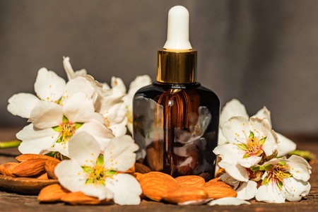 Almonds, oil and white flowers on grey backgroundの写真素材