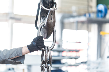 Close-up of worker hand holding crane hook