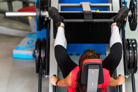 Young sporty woman does leg exercises in gymの写真素材