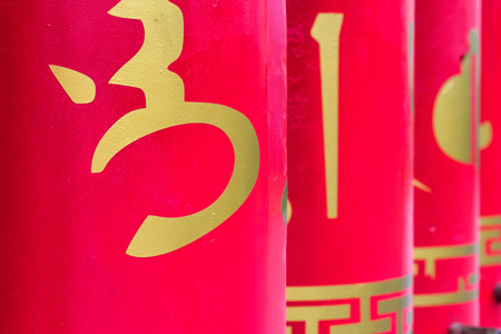 Red buddhist prayer wheels with gold text closeの写真素材