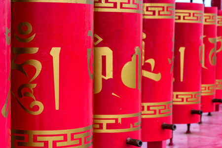 Red buddhist prayer wheels with gold text closeの写真素材