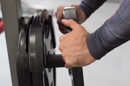 Hands add weigh plates to barbell in gymの写真素材