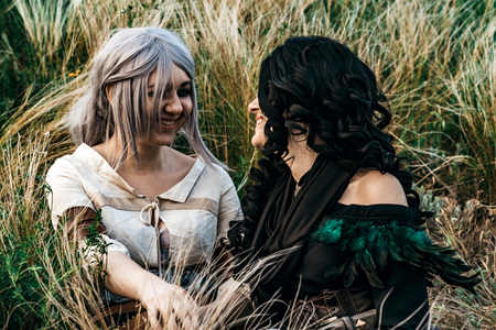Fantasy cosplay two beautiful sit together in grassの写真素材