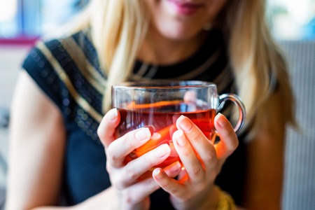 Young blonde woman drinks tea in cafe