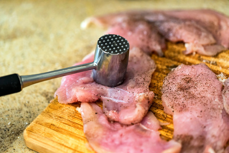 Pounding raw meat with metal hammer closeの写真素材