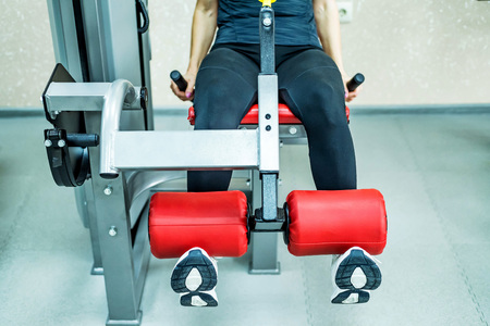 Young woman does leg exercises in gym