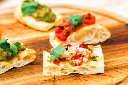 Prawn bruschetta with vegetables on wooden board close up
