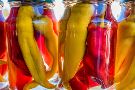 Colorful pickled peppers in glass jars closeの写真素材