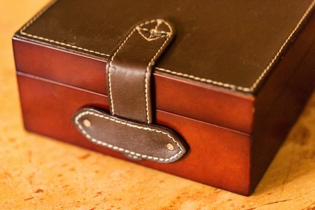 Brown leather box for keeping jewellery on wooden table