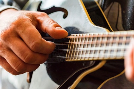 Close up hands of man playing 8-string mandolinの写真素材