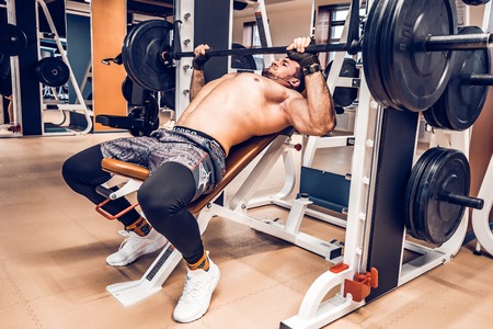 Muscular bodybuilder bench press workout in modern gym