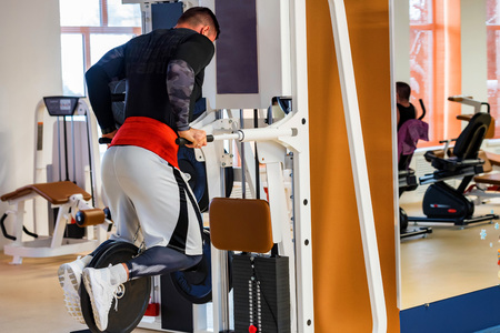Young muscular man does dip exercise in modern gym