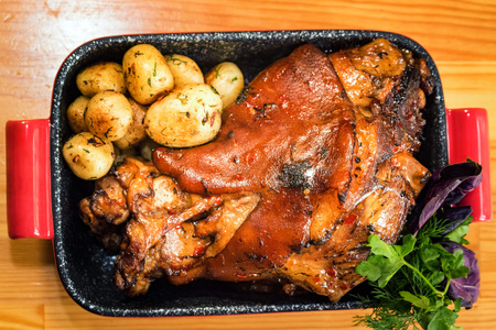 Top view roast pork knuckle served with boiled potatoes in tray