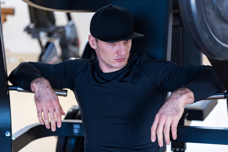 Portrait of male athlete wearing cap sitting at gym