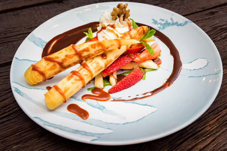 Close up delicious dessert with waffle rolls, ice cream and strawberries
