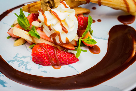 Close up delicious dessert with waffle rolls, ice cream and strawberries