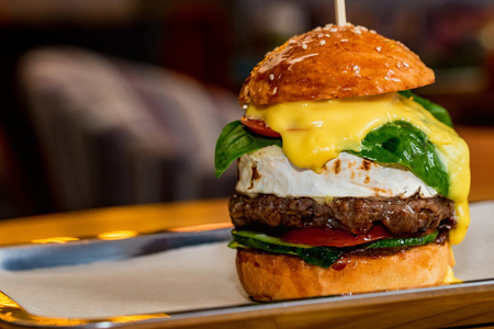 Close up tall tasty burger with cheese served on trayの写真素材