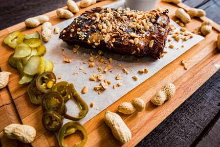 Close up board with pork ribs grilled with BBQ sauce, peanuts and jalapenoの写真素材