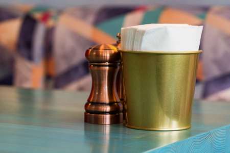 Salt in brown chrome casters and bucket with napkins in restaurantの写真素材