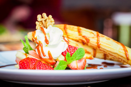 Close up delicious dessert with waffle rolls, ice cream and strawberries