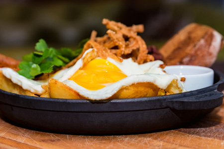 Meal with fried egg, potato wedges, onion rings, chili pepper and sauceの写真素材