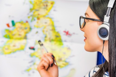 Young beautiful girl with headphones and map of Englandの写真素材
