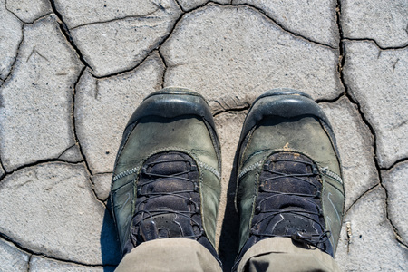 Top view hiking boots on dry muddy soil surface for background textureの写真素材